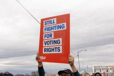 A sign which reads "Still Fighting for Voting Rights"