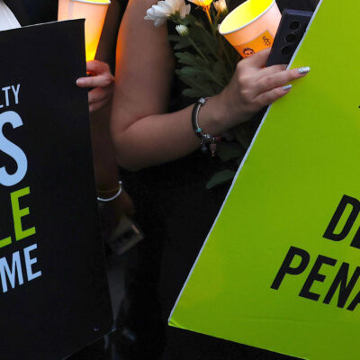 Two demonstrators hold signs that reads "THE DEATH PENALTY KILLS PEOPLE NOT CRIME" and "ABOLISH THE DEATH PENALTY."