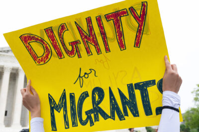 A sign reading "Dignity for Migrants."