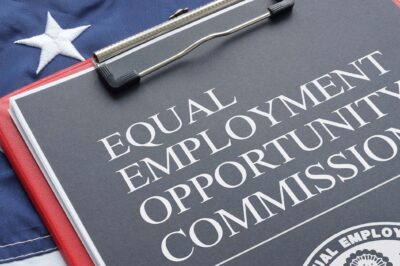 An Equal Employment Opportunity Commission document on a red clipboard that rests on an American flag.