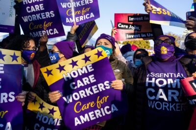 Multiple demonstrators hold up signs that read" "HOME CARE WORKERS CARE FOR AMERICA".