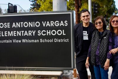 A smiling Jose Antonio Vargas and two equally joyful female family members stand to the right of a large sign that reads "JOSE ANTONIO VARGAS