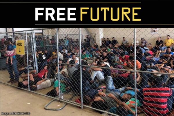 Immigrants behind chain link fence in an overcrowded detention area