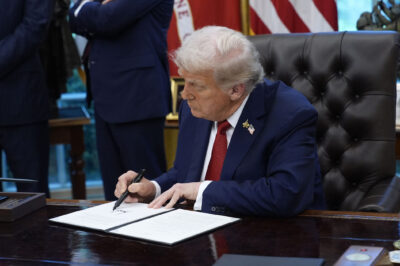 President Trump signs an executive order in the Oval Office of the White House.
