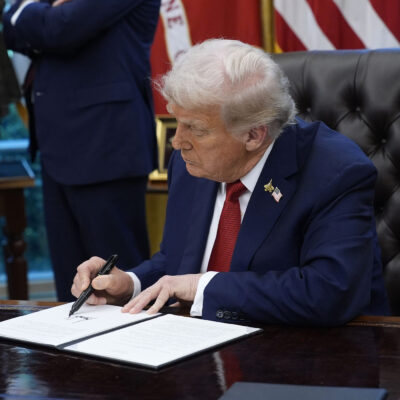 President Trump signs an executive order in the Oval Office of the White House.