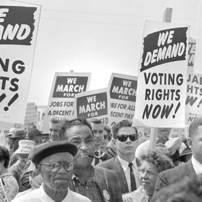 Protesters with signs at march on Washington, D.C. for Jobs and Freedom, carrying signs that read "WE DEMAND VOTING RIGHTS NOW!" and WE DEMAND AN END O POLICE BRUTALITY NOW!" on August 28, 1963.